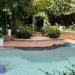 Backyard swimming pool under a green mesh safety cover with floating chlorinators, closed for the off-season