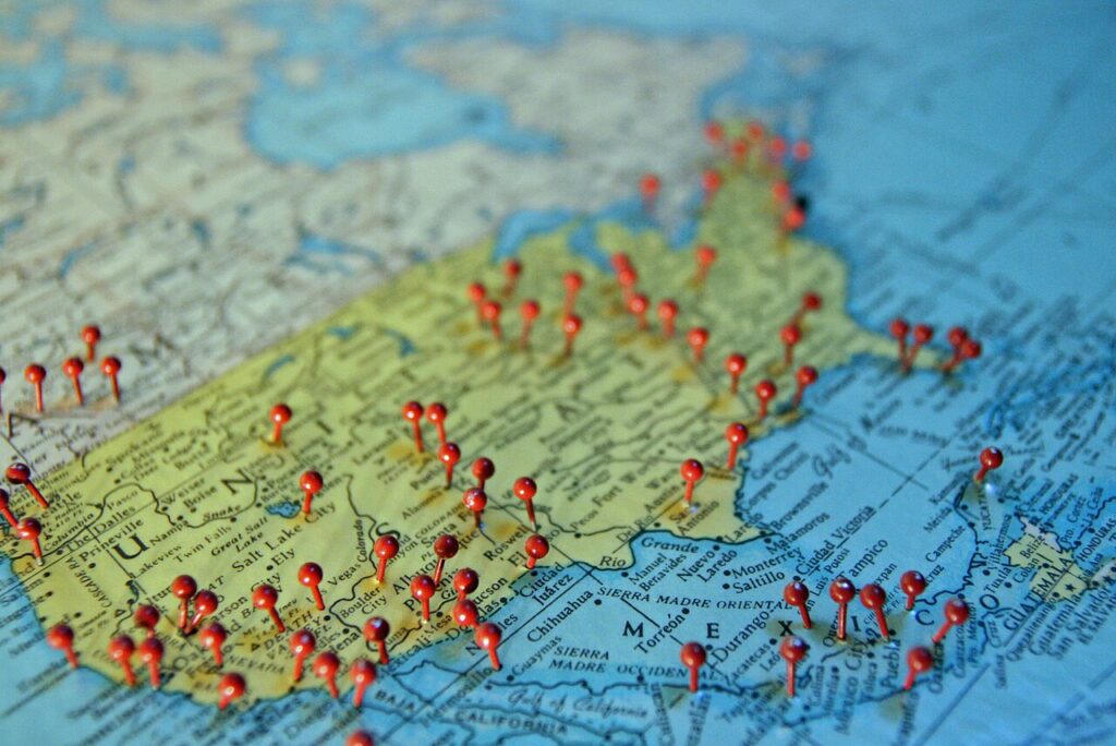 Red pushpins stuck into towns across a paper map of the United States, marking places a business serves