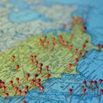 Red pushpins stuck into towns across a paper map of the United States, marking places a business serves